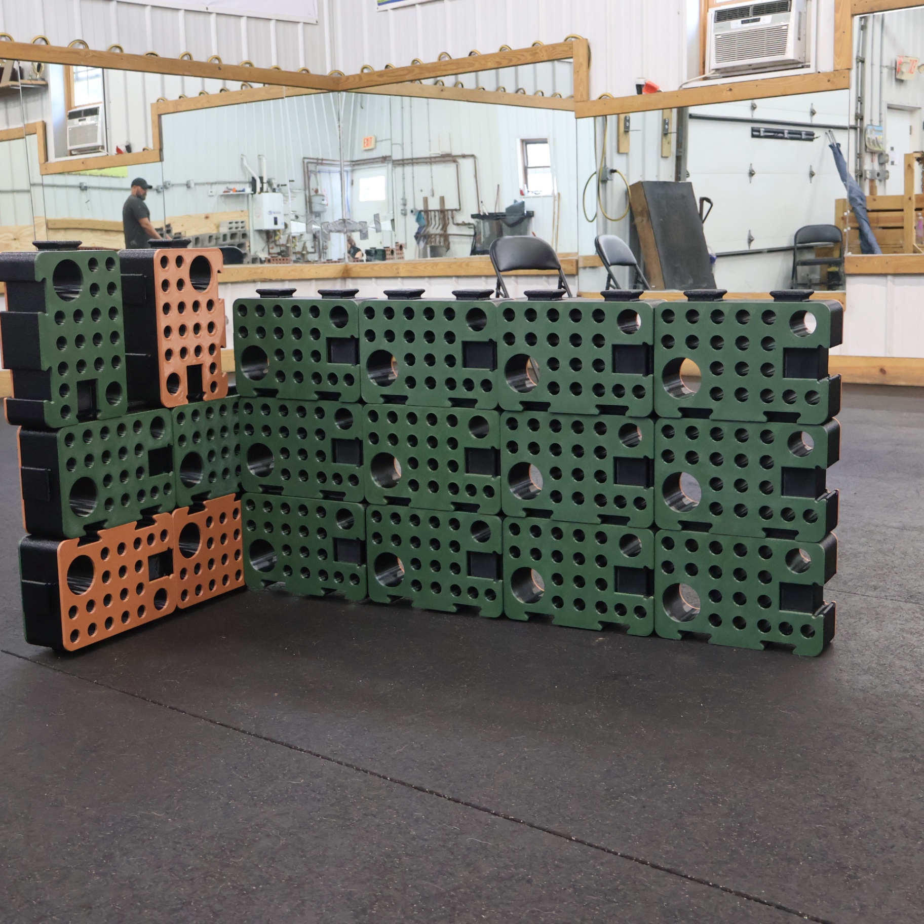 Green and orange D-Blocks assembled into an L-shaped wall in a training facility
