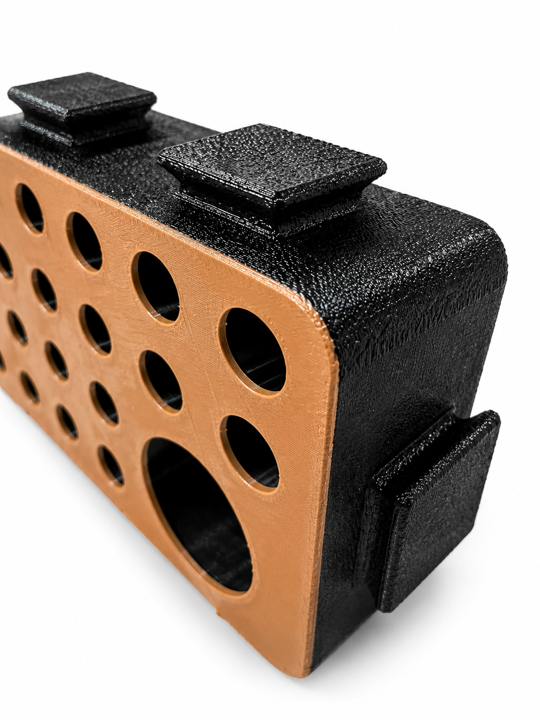 Close-up of an orange D-Block face showing the graduated circular hole pattern and textured black shell