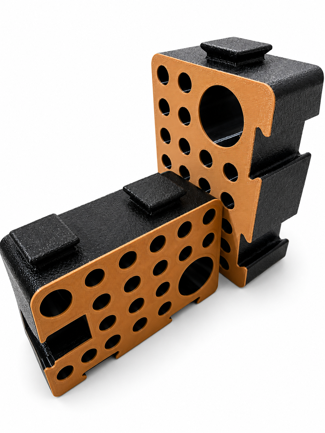 Two orange and black D-Blocks, one upright and one lying flat, showing the drilled hole pattern and interlocking studs